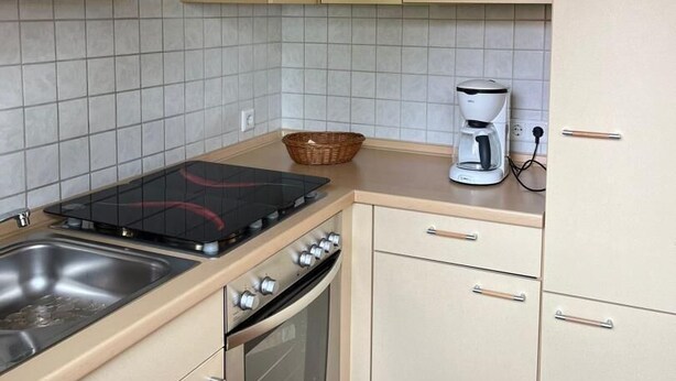 Eine kleine Küche mit Herd, Backofen und Kaffeemaschine.