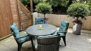 A round table with four chairs, a candle, and potted plants in a patio area. - New! Barbara by the Sea (Horumersiel)