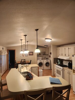 A compact kitchen with a dining area, a washing machine, and a stove.