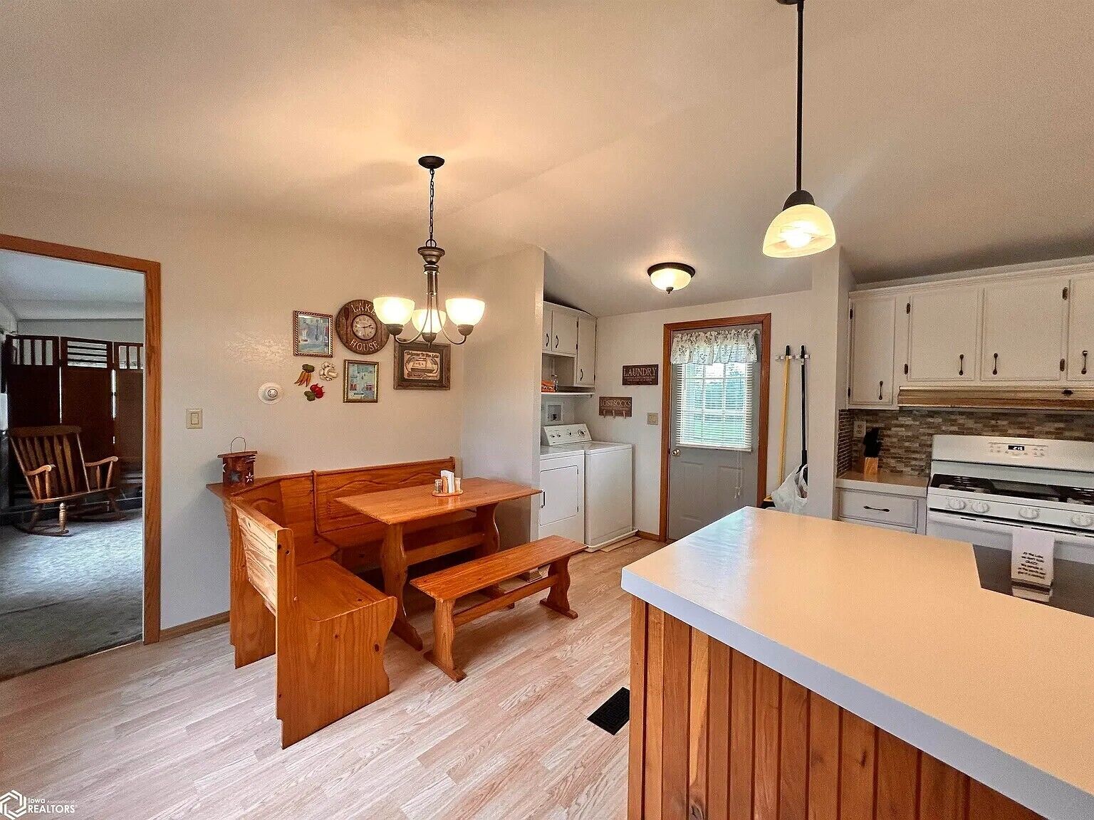 A kitchen with wooden cabinetry, a dining area with a bench, and a built-in island.