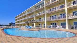 A hotel with a swimming pool, multiple balconies, and lounge chairs. - Coastal Retreat with Pool & Beach Access (Port Aransas)
