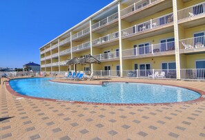 Ein Hotel mit Schwimmbad, mehreren Balkonen und Liegestühlen.