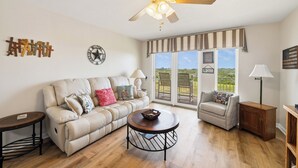 A living room with a ceiling fan, a sofa with cushions, a coffee table, a side table, and a lamp. - Coastal Retreat with Pool & Beach Access (Port Aransas)