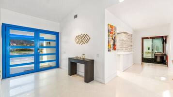 A spacious hallway with a blue door, a console table, and a wall-mounted decorative piece.