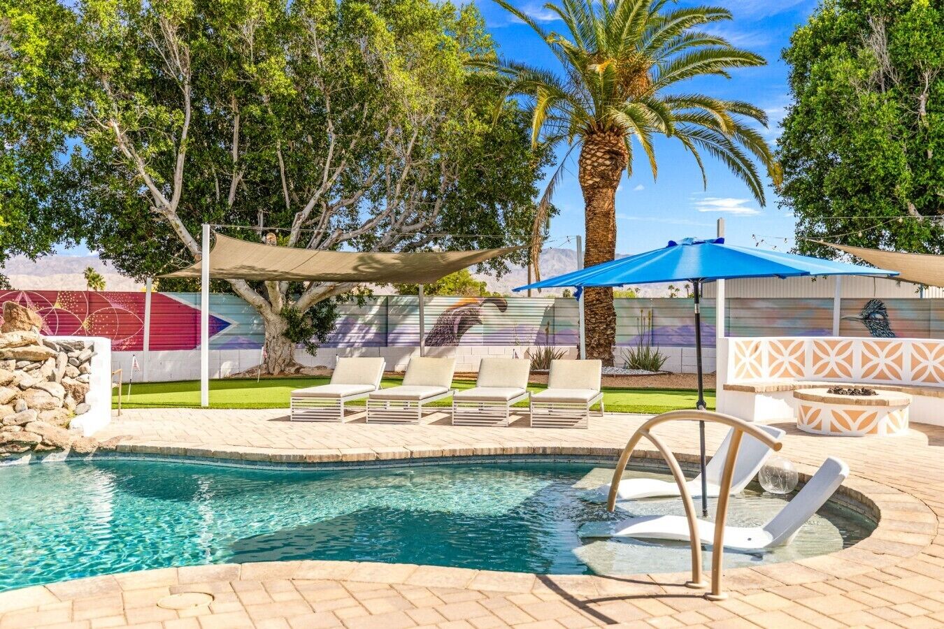 A swimming pool with lounge chairs and a fire pit area.