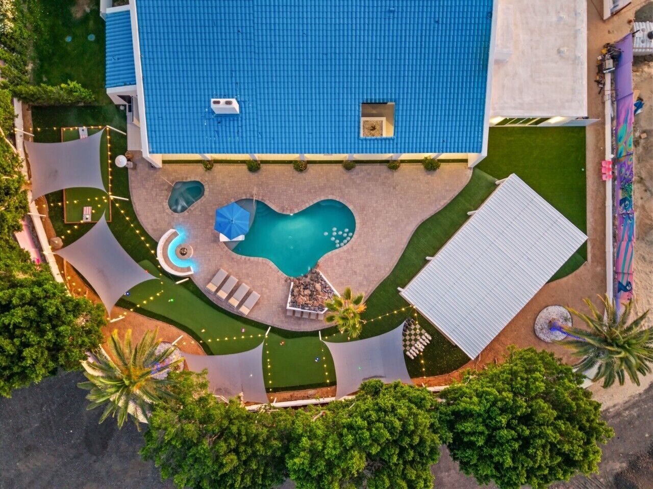 An aerial view of a property with a swimming pool, outdoor seating, and a covered area.