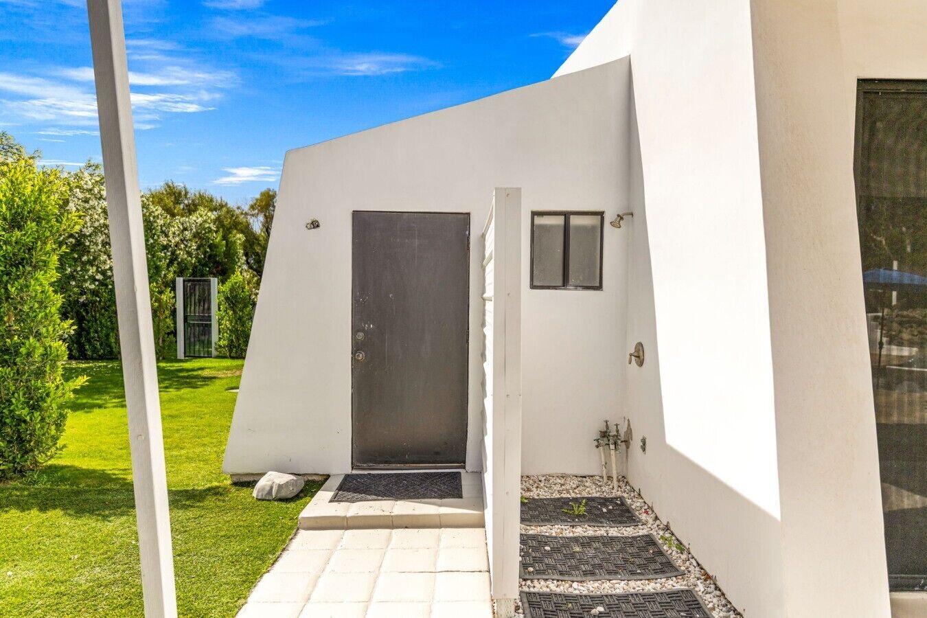 Un edificio moderno con fachada blanca, una puerta y un ventanal pequeño.