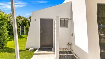Un edificio moderno con fachada blanca, una puerta y un ventanal pequeño.