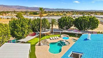 A residential property with a swimming pool, lounge chairs, and a view of distant mountains.
