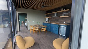 A modern kitchen with blue cabinets, a dining area with wooden chairs, and a small refrigerator. - 1 bedroom guesthouse with volcano views throughout the home in Juayua (Juayua)
