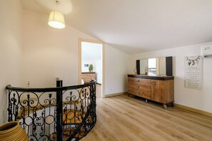 A spacious room with a wooden floor, a black wrought iron railing, a wooden cabinet, and a ceiling light fixture. - Cristal 4 Apartment (Cannes)