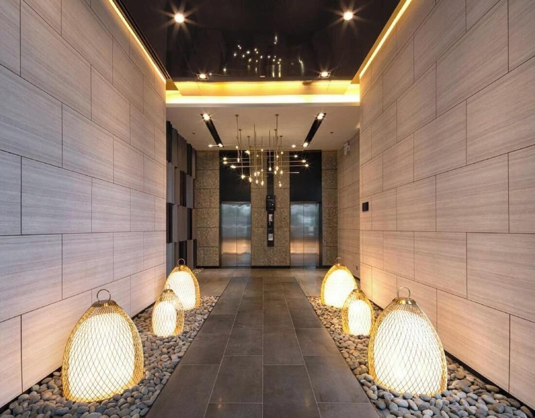 A modern hallway with a tiled floor, decorative lighting, and a central chandelier.