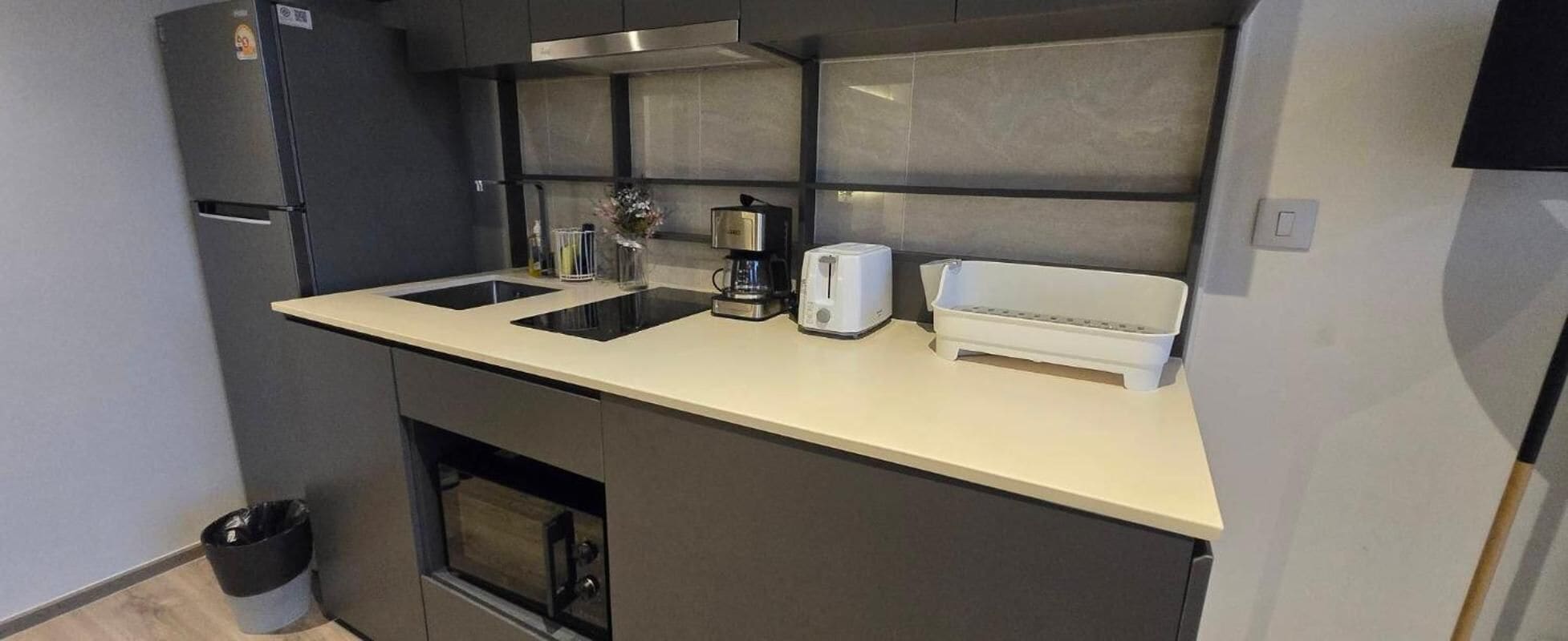 Une cuisine compacte équipée d’un four encastré, d’une machine à café et d’un grille-pain.