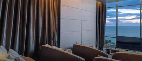 A hotel room with a large window, a flat-screen TV, and a seating area with a sofa and chairs.