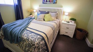 A bedroom with a bed, bedside tables, a nightstand, a lamp, a potted plant, and a painting on the wall. - Steps to Beach, Zen balcony, Pier Park & more (Panama City Beach)