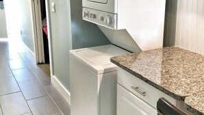 A compact kitchen with a built-in oven, a washing machine, and a countertop. - Steps to Beach, Zen balcony, Pier Park & more (Panama City Beach)