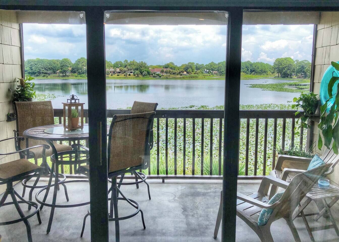 Ein überdachter Außenbereich mit Tisch und Stühlen, Blick auf einen See und einer Geländer.