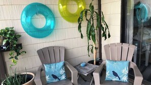 Two chairs with blue cushions, a potted plant, and two inflatable rings on a wall. - Steps to Beach, Zen balcony, Pier Park & more (Panama City Beach)
