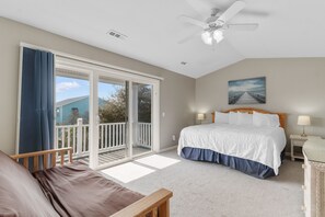 A bedroom with a bed, a nightstand, a ceiling fan, a painting, and a balcony. - The Rivalry House 10 Bedroom W/ Private Pool and Short Walk to Beach (Surfside Beach)