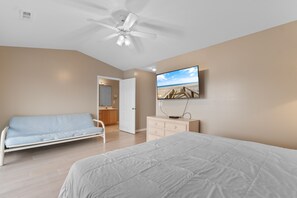 Une chambre à coucher avec un lit, un canapé, une télévision et un ventilateur de plafond.