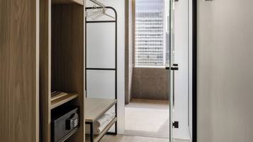 Une chambre d’hôtel moderne avec un lit superposé, une armoire et une vue sur le paysage urbain grâce à une grande fenêtre.