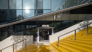 Un bâtiment moderne avec une façade en verre, un escalier aux marches jaunes et une enseigne indiquant « yotel ».