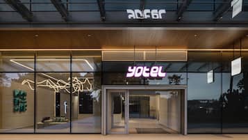 A modern hotel entrance with glass doors and a neon sign.