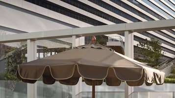 Een moderne terrasruimte met twee ligbedden en een grote parasol.
