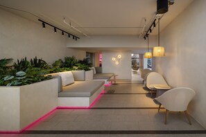 A modern interior with a seating area, plants, and a view of the outside. - YOTEL Bangkok Sukhumvit (Bangkok)