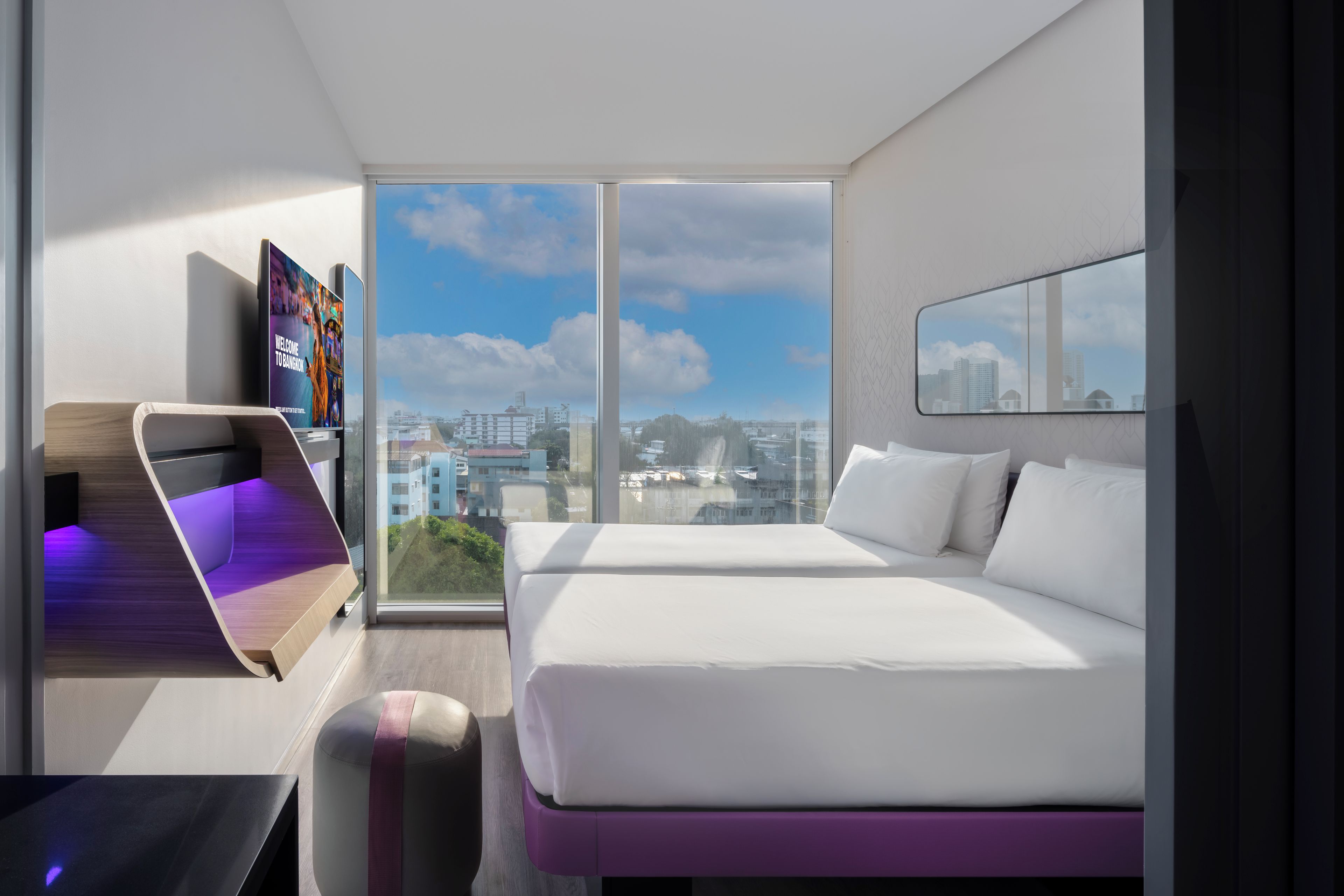Ein modernes Hotelzimmer mit einem großen Bett, einem Fernseher und Blick auf die Stadt.