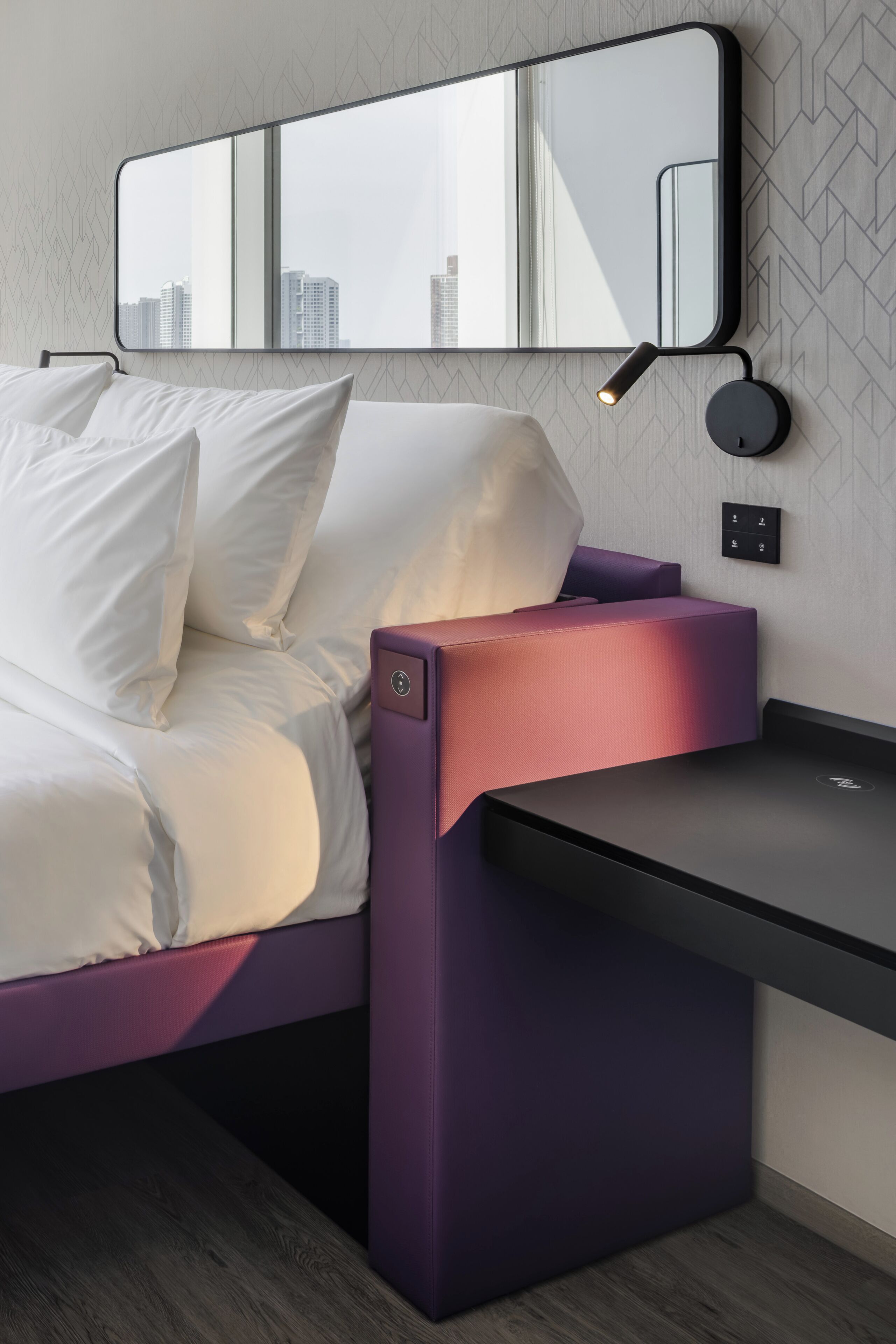 A modern bedroom with a bed, a desk, and a mirror.