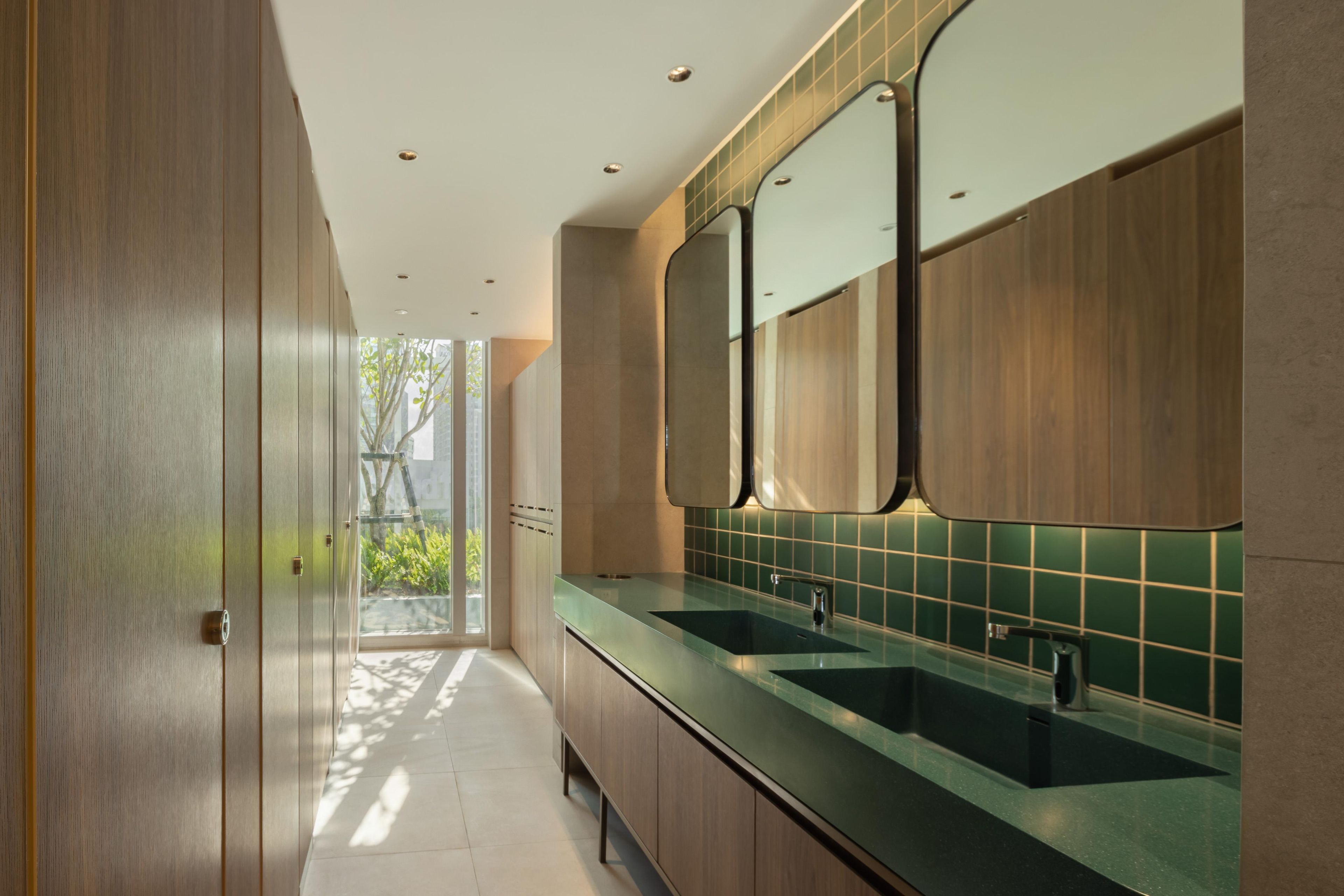 Een moderne badkamer met houten kastjes en een groene tegeltjeswand.