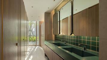 Een moderne badkamer met houten kastjes en een groene tegeltjeswand.