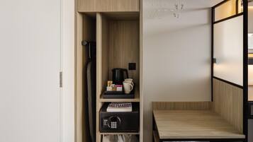 A compact room with a built-in wardrobe, a small seating area, and a drying rack.