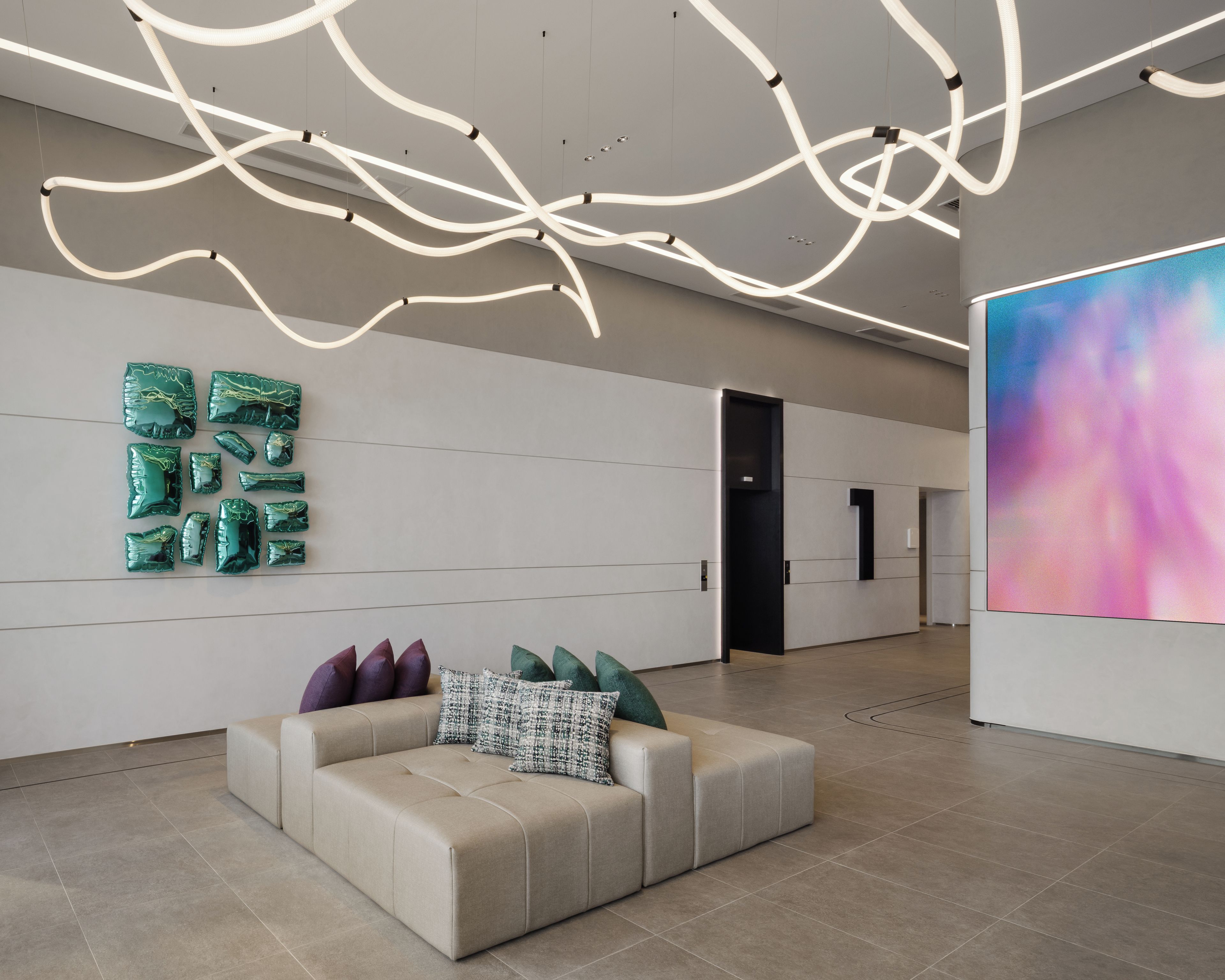 A modern interior with a sofa, abstract art, and a unique ceiling light design.