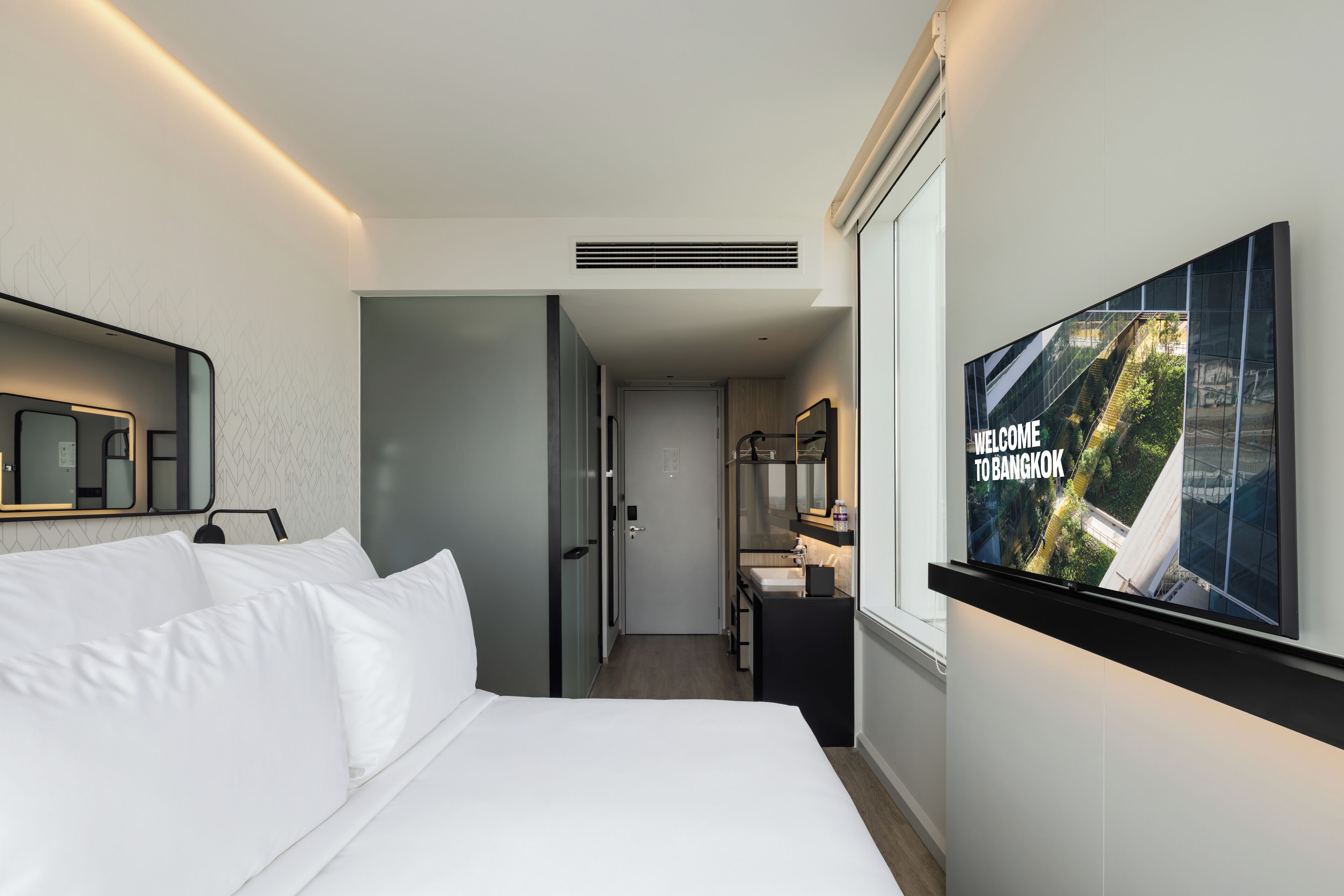 Una habitació d'hotel amb un llit, televisió i bany.