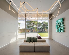 A modern interior with a sofa, a hanging light fixture, and a view of the outdoors. - YOTEL Bangkok Sukhumvit (Bangkok)