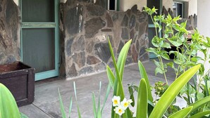 A building with a stone wall, a green door, and a hanging lantern. - Rancho Meling Mountain Cabin #3 with Pool and Views (Baja California)