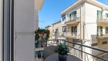 Ein Balkon mit einer Topfpflanze, einem runden Tisch und Blick auf angrenzende Gebäude.