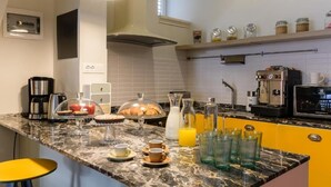 A kitchen with a marble countertop, coffee maker, toaster, and breakfast items.