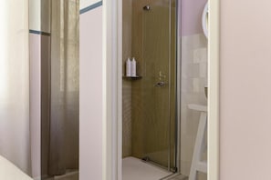 A glass-enclosed shower area with a wooden door, a white towel rack, and a white chair. - Unico Art Decor (Ostuni)