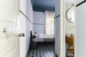 A bedroom with a bed, a bedside table, a mirror, and a bathroom with a toilet and sink. - Unico Art Decor (Ostuni)