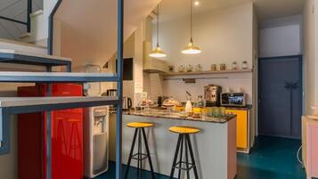 Eine moderne Küche mit Kochinsel, Barhocker und Kühlschrank.