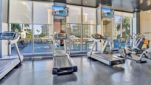 Une salle de sport équipée de tapis de course, d’un rameur et d’un écran de télévision.