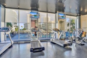A gym with treadmills, a rowing machine, and a TV screen. - Ocean & Canal View Studio Beach 8 Min Pool Gym 804 (Hallandale Beach)