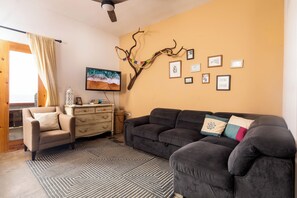Ein Wohnzimmer mit einer Couch, einem Sessel und einem dekorativen Zweig an der Wand.