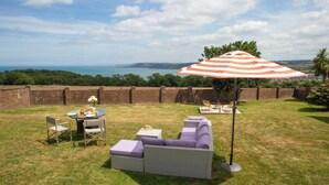 An outdoor seating area with a table, chairs, a sofa, and an umbrella. - 3 Hilltop Way, Aberporth (Aberporth)
