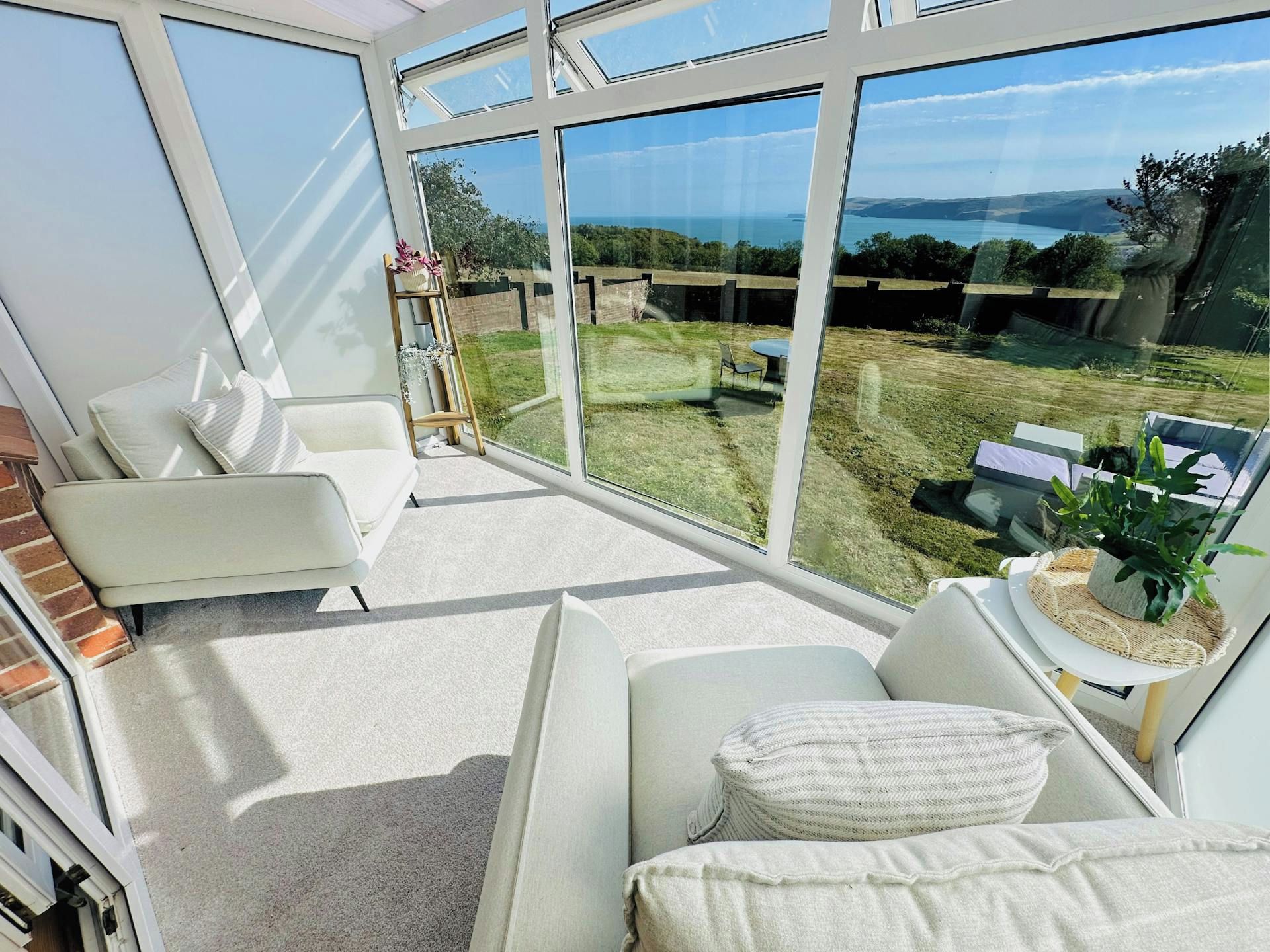 A modern interior with a large glass window, a white sofa, and a small table with a plant.