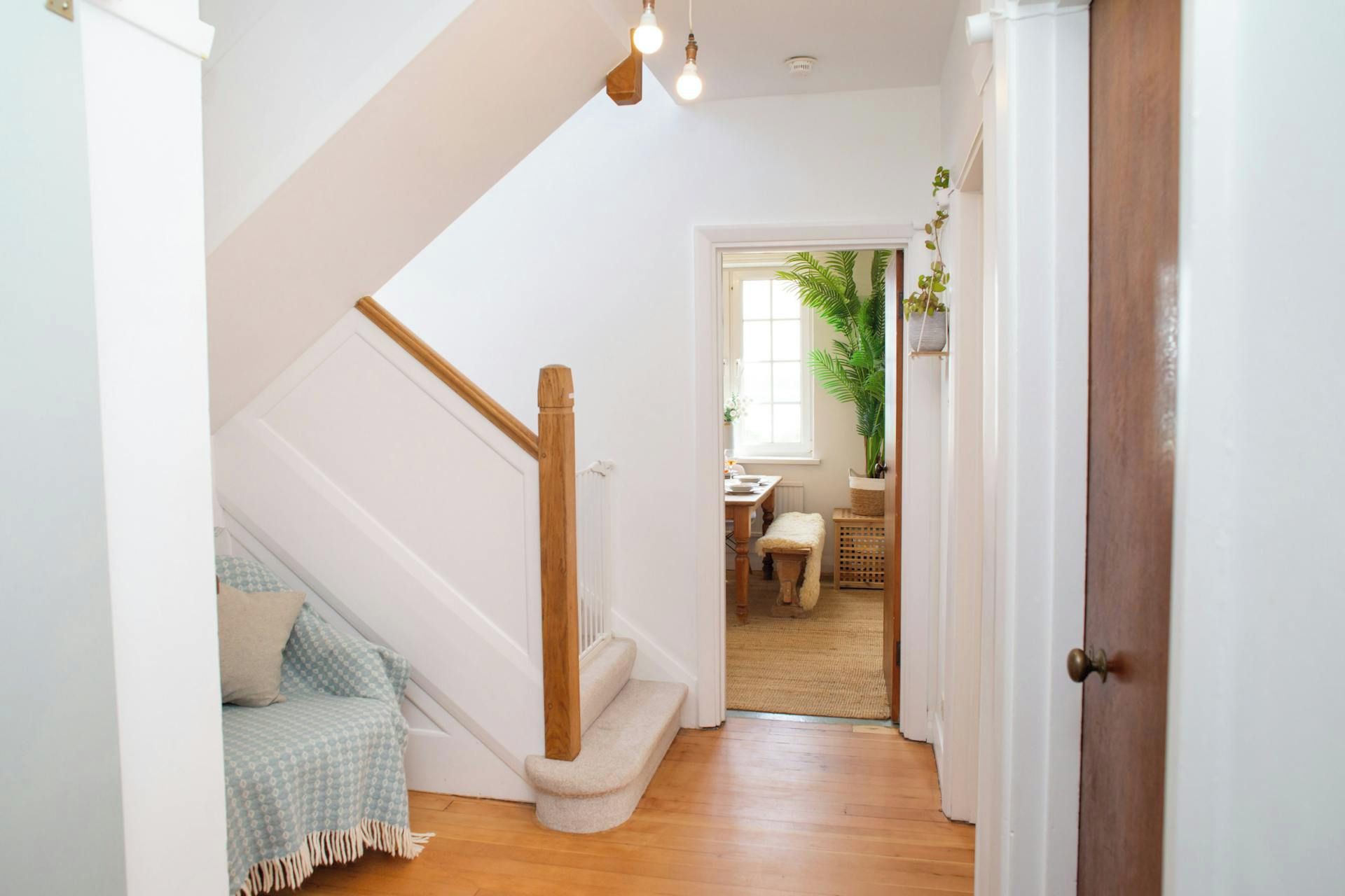 Un escalier avec une rampe en bois menant à une pièce où se trouvent un lit et un banc.