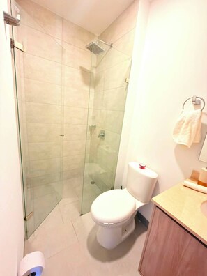 A bathroom with a glass-enclosed shower, a toilet, and a sink with a towel hanging on the wall. - 🌴 Caribbean Resort-Style Paradise: Ocean Views, Pools, and Relaxation in Santa Marta (Santa Marta)